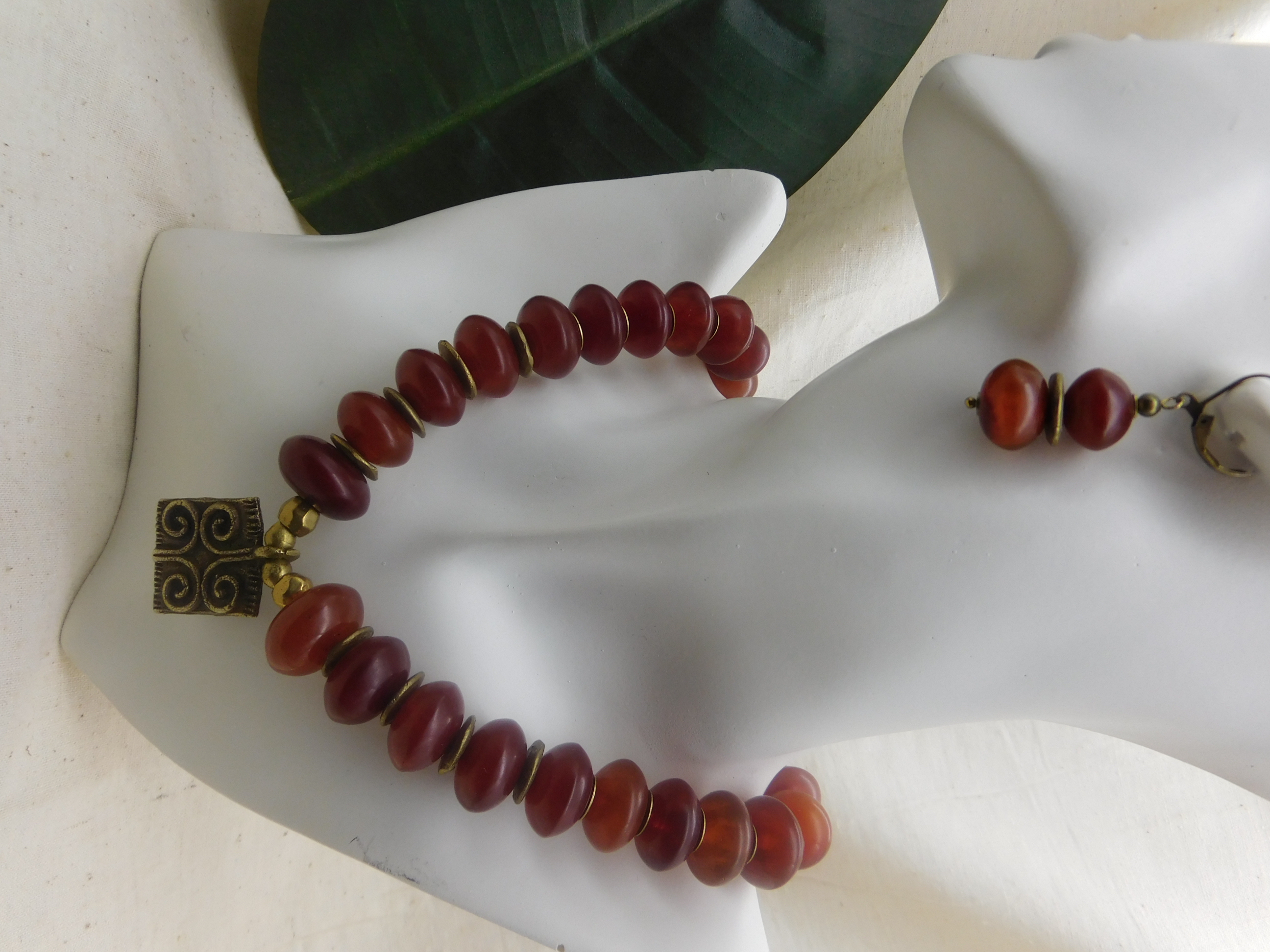 African inspired necklace with resin amber beads and a handmade brass pendant with a Sankofa symbol
