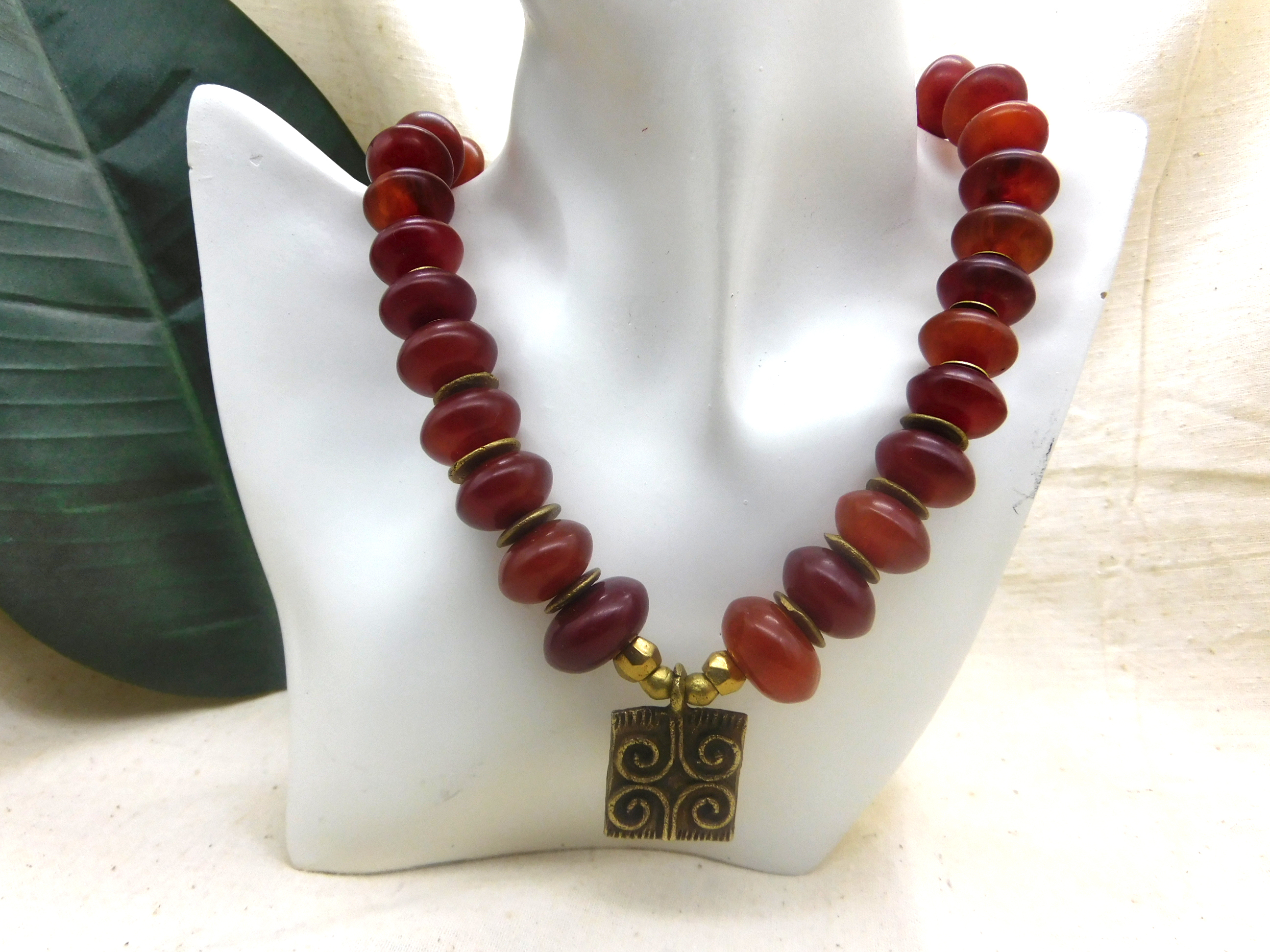 African inspired necklace with resin amber beads and a handmade brass pendant with a Sankofa symbol